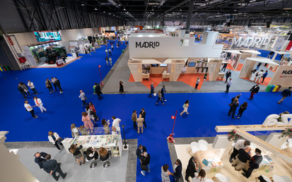 Top down view on people at exhibitions stands at event hall IFEMA Madrid with blue event carpet pathways between white booths