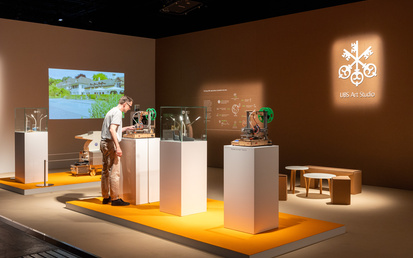 Art exhibition stand with art objects on display on top of orange event carpet