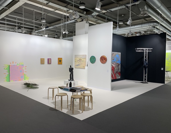 artistic black and white exhibition stand with stools around a small table on dark grey and white latex-free carpet