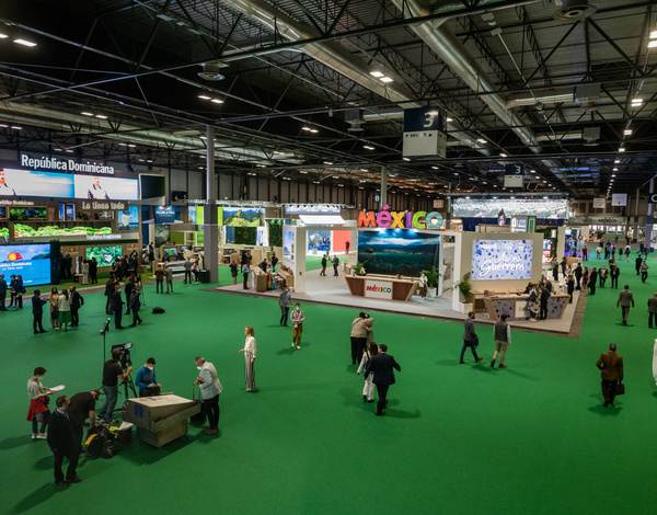 Spring green recyclable carpet floor in big event venue with people walking around small exhibition booths