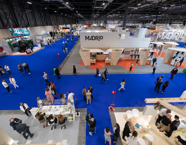 Top down view on people at exhibitions stands at event hall IFEMA Madrid with blue event carpet pathways between white booths
