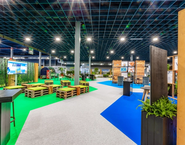 Exhibition booths at VIV Europe inside of big event hall around sustainable carpet path in grey, blue and green